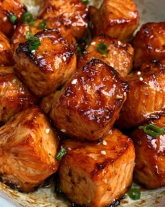 Crispy honey garlic salmon bites served with a side of fresh vegetables.